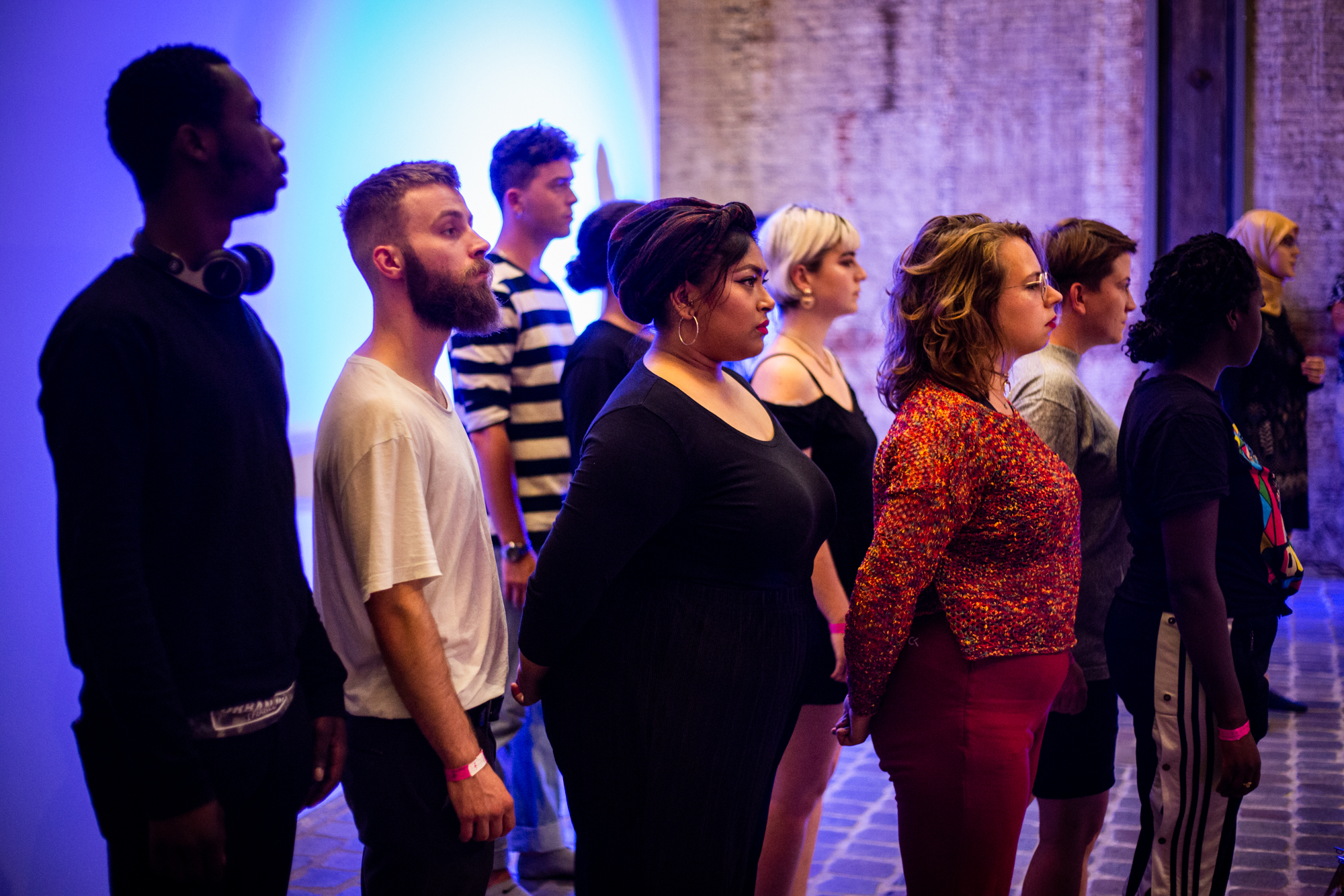 A group of young people are stood looking out into an audience in a museum.