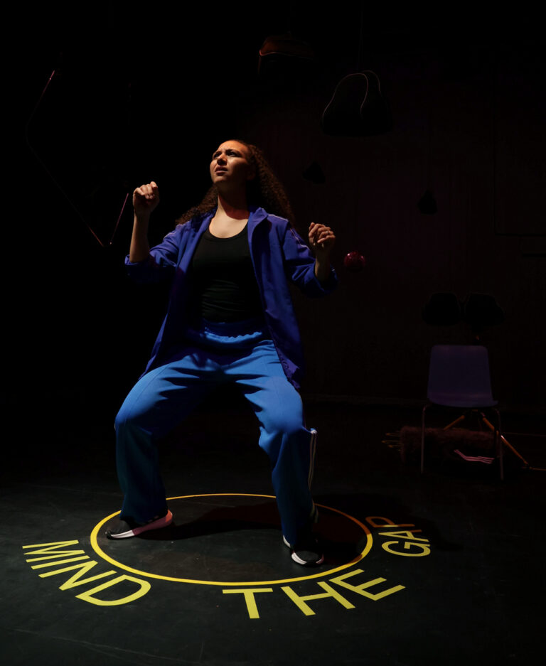 Actress Lauren Fitzpatrick is crouching in an action shot from play 14%. She is stood in a circle labelled Mind the Gap.