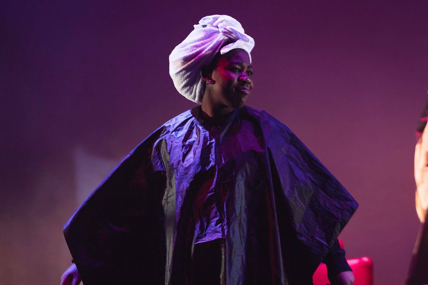 *insert name* in a towel head wrap and salon cape smiling